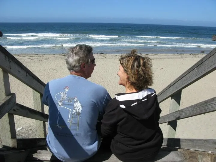 A couple sitting on the beach stairs, looking out to sea