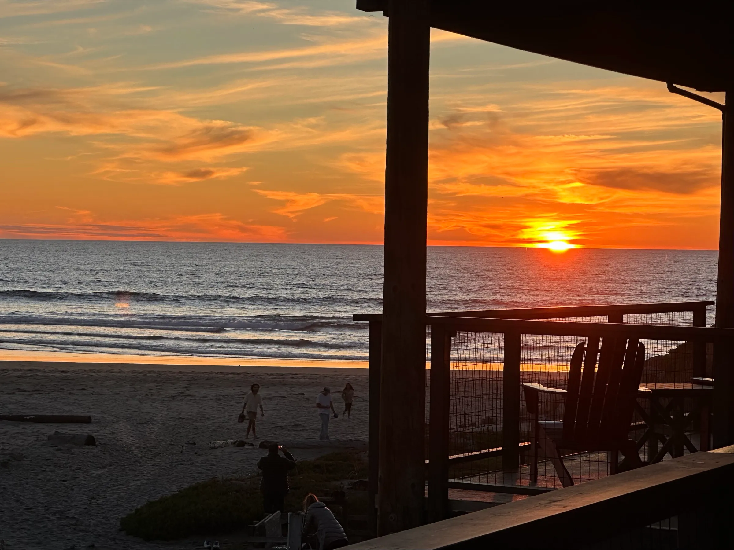 Sunset over the ocean from the balcony, with people on the beach below